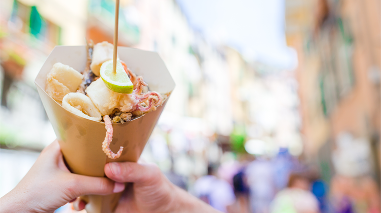Foto di mani che tengono in mano un cartoccio di pesce fritto: boom dello street food e dei siti di personalizzazione del packaging