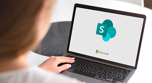 ragazza che lavora al pc mentre sul monitor si vede il logo di sharepoint
