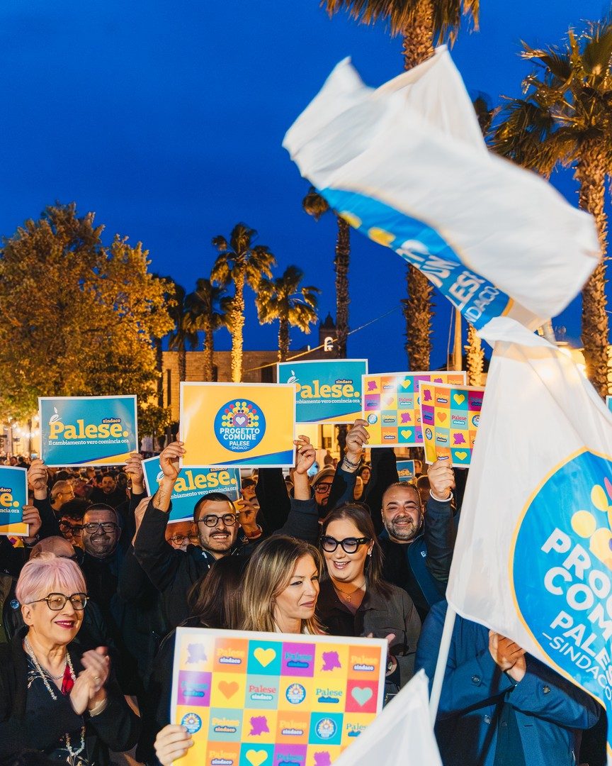 Gruppo di persone che assiste al comizio con cartelli e bandiere