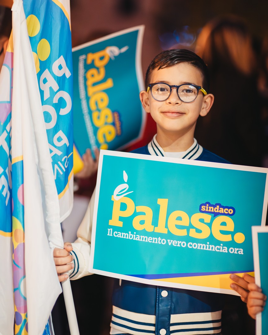 Foto di un bambino con un cartello "Palese sindaco" in mano