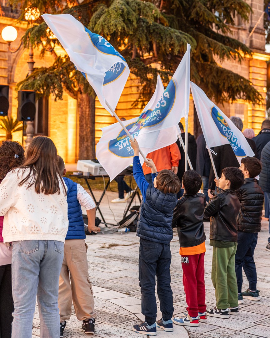 Gruppo di bambini che assiste al comizio con cartelli e bandiere
