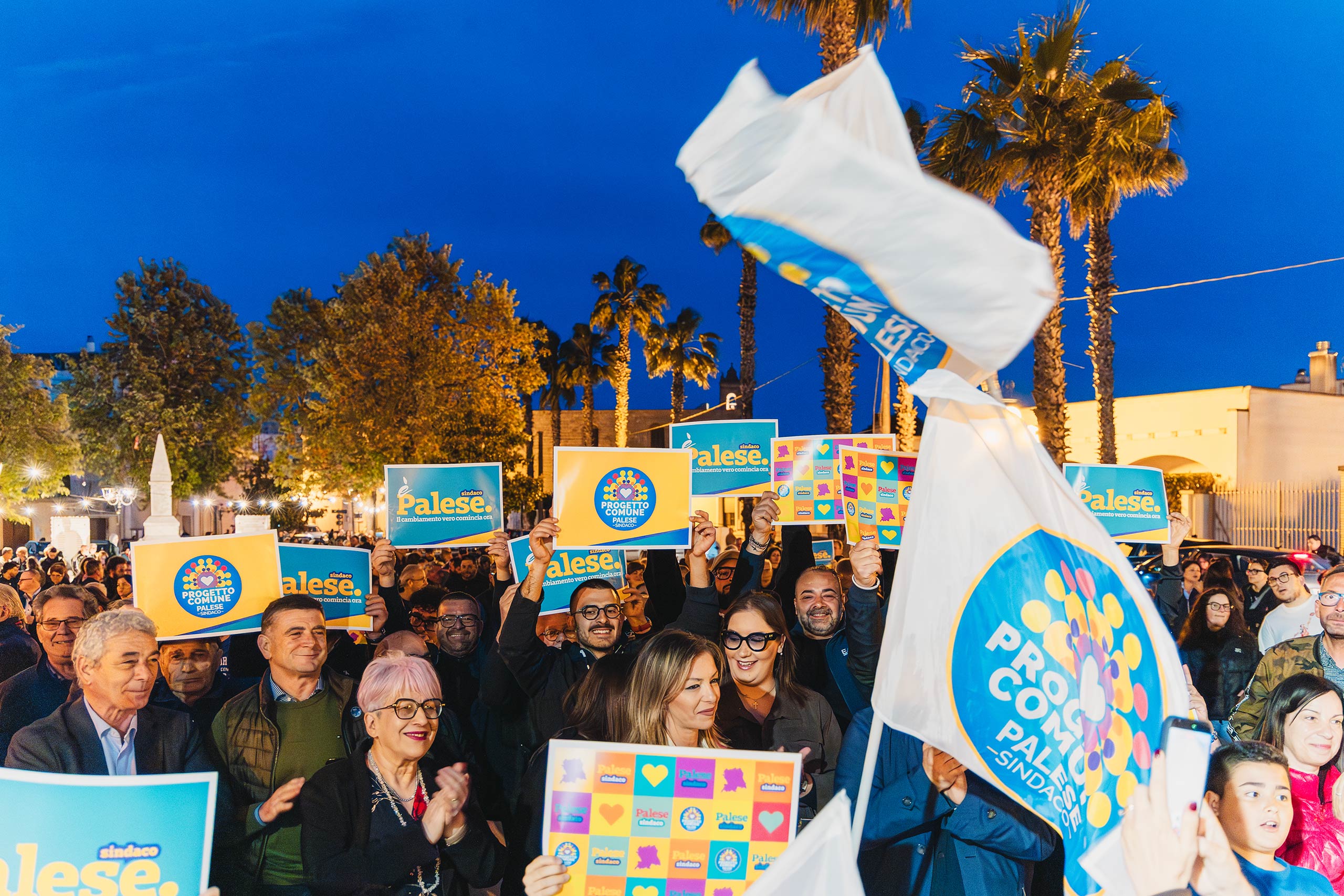 Gruppo di persone che assiste al comizio con cartelli e bandiere